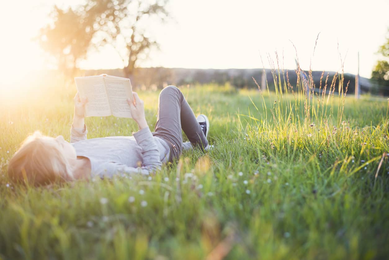 Girl reading a book outside header achieving while letting go